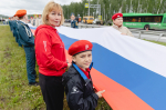 На фото — патриотическая акция на трассе: большая группа людей развернула длинный флаг России на разделительной полосе автомагистрали, Изображение.